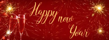 Mutlu yıllar 2022 - Şenlikli gümüşi arka plan panorama afişi uzunluğunda - altın sarısı havai fişek ve kırmızı dokuda kadeh kaldıran iki şampanya sınıfı