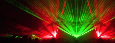 Lasershow festivali disko partisi arka plan panoraması - ışın akımları ve parti insanlarının kalabalık silueti ile renkli açık hava lazer gösterisi