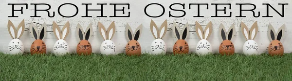 快乐的复活节背景贺卡 许多褐色和白色的复活节彩蛋 有兔子耳朵 复活节兔子在新鲜的绿色草地上 与白色的古董色墙质感隔离 — 图库照片