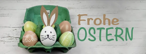 快乐的复活节背景横幅全景贺卡 来自色彩艳丽的彩绘彩蛋和绿色蛋盒中的东方兔子在质朴的白色老式破旧木桌上的特写 — 图库照片