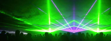 Lasershow festivali disko partisi arka plan panoraması - ışın akımları ve parti insanlarının kalabalık silueti ile renkli açık hava lazer gösterisi