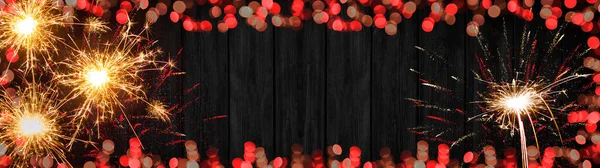 シルベスターパーティー新年花火の背景バナーパノラマ長い 文字のためのスペースと素朴な黒の木のテクスチャに赤いボケライトで作られた花火やフレーム — ストック写真