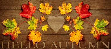 Merhaba sonbahar - Arkaplan, pek çok farklı rengarenk sonbahar renkli soyut akçaağaç yapraklarının üst görünümü koyu kahverengi ahşap masa dokusu, harfler ve kalp ile izole