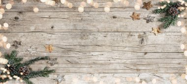 Festivalsel dekoratif Noel / Advent arkaplanı - Noel süsü köşe afişi, köknar dalları, yıldızlar, çam kozalakları ve bokeh ışıkları - kırsal bir ahşap masa zemininde manzaranın üzerinde.