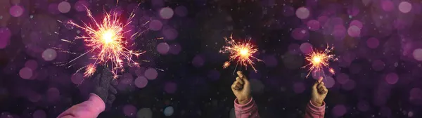 Silvester / Party / New Year / Celebration / wedding background - Happy girl and woman holding sparkling sparklers in her hands at dark night with pink bokeh lights