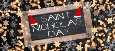 Aziz Nicholas Günü afiş şablonu - Noel Baba şapkası, bokeh ışığı, yıldızlar ve buz kristalleri, koyu siyah kırsal ahşap masa dokusunda izole edilmiş