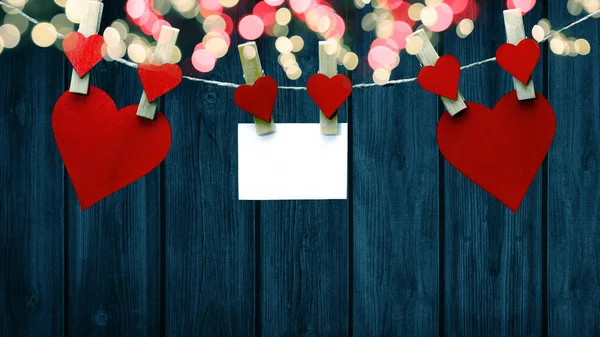 情人节快乐的背景 红色的心和白色的纸条挂在木制的衣服钉上 木制的心 蓝色的木墙上的绳子上挂着防盗灯 上面有文字的空间 — 图库照片
