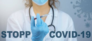 CORONAVIRUS STOP COVID-19 / CORONA VACCINATION - Genç bayan doktorun elinde kırmızı çizgi film virüsü sembolü olan Corona aşısı olan bir şırınga bulunduruyor