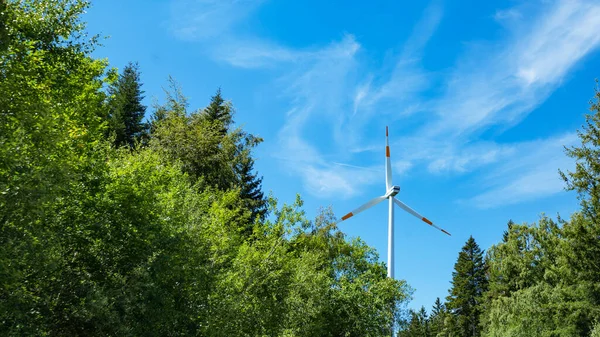 Rüzgar enerjisi arka plan pankartı geniş panoramik panorama - Almanya 'da ormanda birçok rüzgar türbini, güneş ışığı ve yeşil ağaçlara sahip mavi bulutlu gökyüzü (Kara Orman )