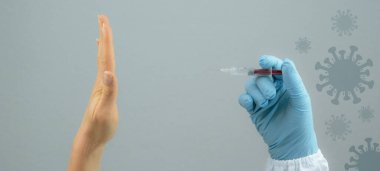 CORONAVIRUS COVID-19 / CORONA VAKANLIĞI: HİÇ AŞIK YOK, doktor elinde Corona aşısı olan şırıngayı tutuyor, genç kadının eli aşıyı reddediyor (dur, hayır )