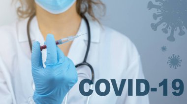 CORONAVIRUS COVID-19 / CORONA VACCINATION - Genç bayan doktorun elinde kırmızı çizgi film virüsü sembolü olan Corona aşısı olan bir şırınga var