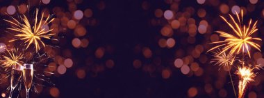 YILI YIL 2022 / Yeni Yıl Arifesi Parti Havai fişeği - Bayram gümüşü arka plan panoraması uzun - Altın havai fişekler ve şampanya sınıfları Bokeh ışıklarıyla karanlık gökyüzü dokusunda kadeh kaldırıyor
