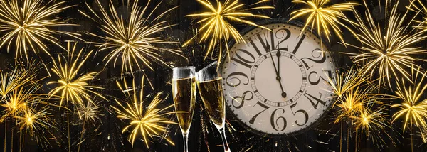 HAPPY NEW YEAR 2022 - Festive silvester New Year\'s Eve Party background panorama banner long - Golden yellow fireworks, clock and champagne classes toasting on rustic black wooden wall texture in the night