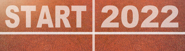 New year 2022 or start straight concept background banner panorama. Word START 2022 written on the orange running track on sports field with arrow, top view