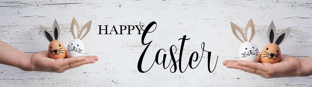 Happy Easter background banner panorama greeting card - Young women holding Easter eggs with bunny ears / Easter bunnies in their hands, isolated on white vintage shabby wall texture