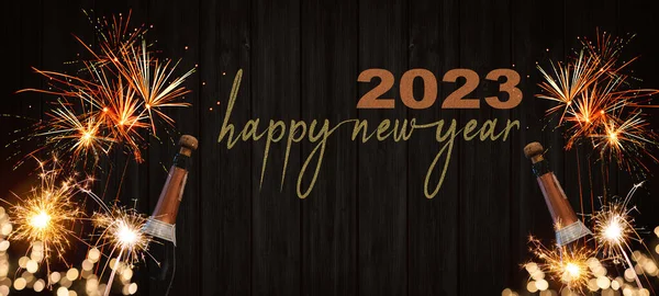 Yeni yılın kutlu olsun 2023 Silvester Yeni Yıl Partisi arka plan afişi havai fişekli şampanya şişeleri ve gecenin ahşap duvar dokusunda maytap.