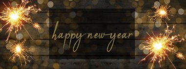 Yeni yılınız kutlu olsun panorama afişi... Maytaplar, havai fişekler ve kırsal siyah ahşap dokuma / ahşap tahta duvardaki bokeh ışıkları.
