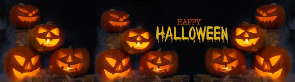 Scary Halloween celebration holiday background banner panorama - Spooky carved pumpkins and dust in the dark black night