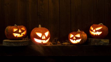 Scary Halloween celebration holiday card - Spooky carved pumpkins and dust on dark wooden wall wood background