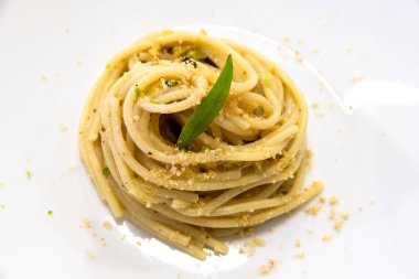 Şam fıstıklı spagetti tabağı ve beyaz arka planda izole edilmiş kızarmış ekmek kırıntıları.