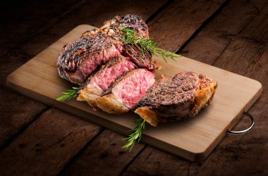Fiorentina T-bone steak cut on rectangular wooden chopping board isolated on rustic wooden background