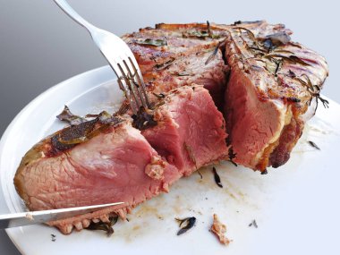 Beyaz arka planda yuvarlak beyaz bir tabakta kesilmiş ızgara Floransa bifteği.