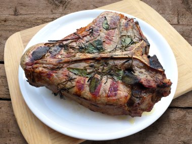 Beyaz yuvarlak tabak ve ızgara biftek. Köy tahtasında izole edilmiş.