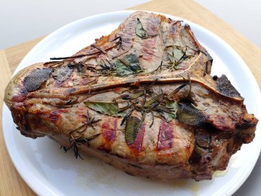 Bütün beyaz yuvarlak plakalı beyaz arka plan üzerinde izole T-bone biftek ızgara