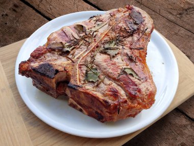 Beyaz yuvarlak tabak ve ızgara biftek. Köy tahtasında izole edilmiş.