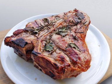 Bütün beyaz yuvarlak plakalı beyaz arka plan üzerinde izole T-bone biftek ızgara