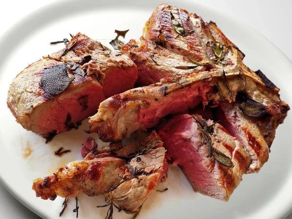 Beyaz arka planda kesilmiş ızgara fiorentina biftekli beyaz yuvarlak tabak.