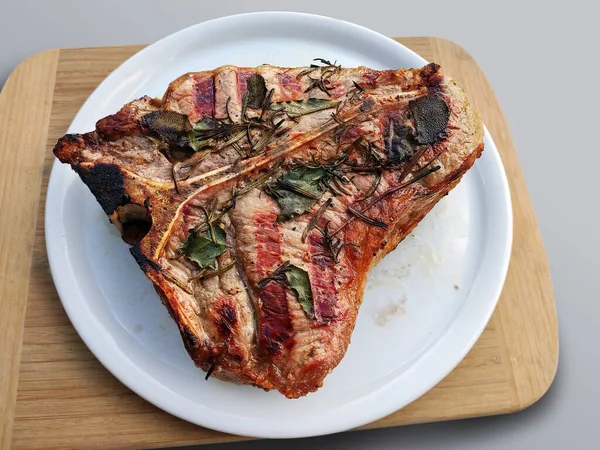 Bütün beyaz yuvarlak plakalı beyaz arka plan üzerinde izole T-bone biftek ızgara