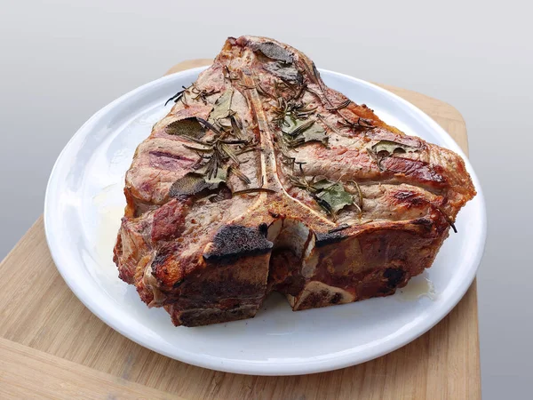 Bütün beyaz yuvarlak plakalı beyaz arka plan üzerinde izole T-bone biftek ızgara