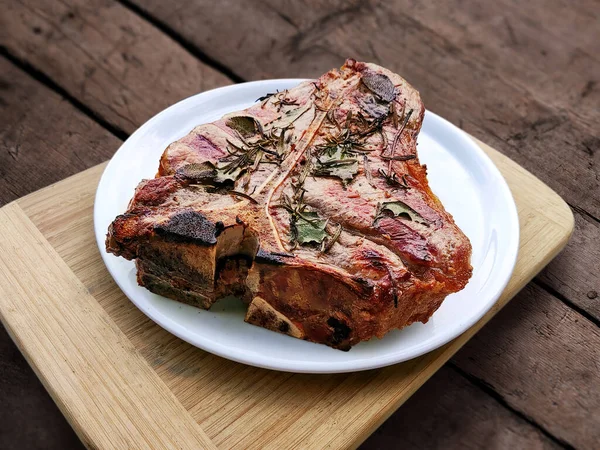 Beyaz yuvarlak tabak ve ızgara biftek. Köy tahtasında izole edilmiş.