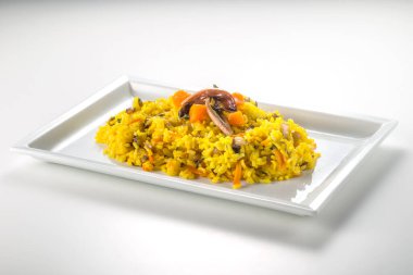 Safran pirinçli dikdörtgen tabak geç turşu ve beyaz arka planda sarı balkabağı.