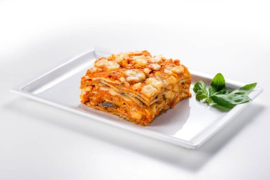 Beyaz arka planda domates peyniri ve fesleğen yapraklı patlıcanlı dikdörtgen yemek.