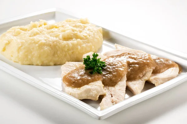 Rectangular plate with slices of white meat and mashed potatoes isolated on white background