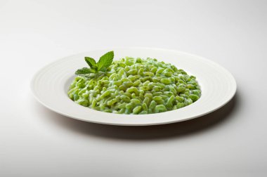 Beyaz arka planda izole edilmiş nane yapraklarıyla süslenmiş yeşil sebzeli pilav tabağı.