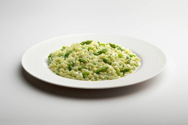 Beyaz masaya izole edilmiş yeşil kuşkonmaz ile beyaz düz pilav tabağı.