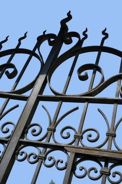 Detail of ancient wrought iron gate on blue sky