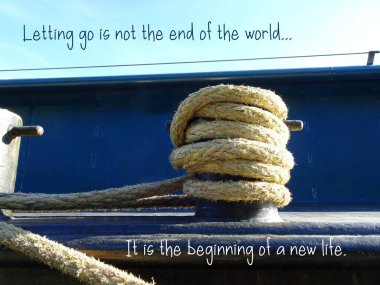 Maritime mooring rope on a boat. Close up. Boat moored at the pier. Text quote 'Letting go is not the end of the world. It is the beginning of a new life.'