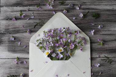 a vertical shot of a beautiful bouquet of lilac and wildflowers on a wooden background