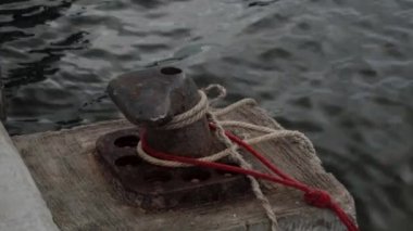 İskeleye demirlemiş balıkçı teknelerinin ipleriyle paslanmış eski bir demirleme borusu.