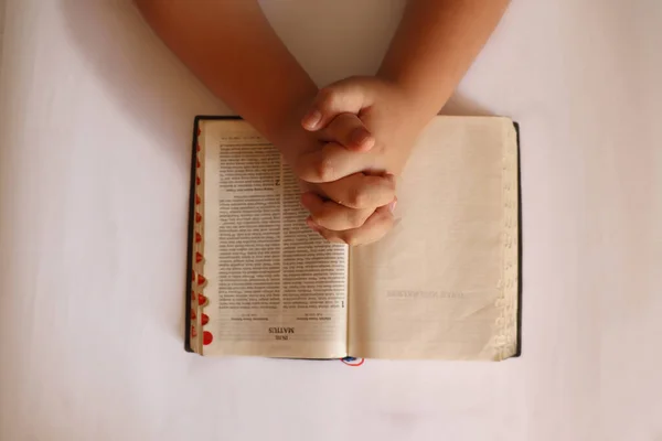 A Person is Folding Hands on the Bible in Indonesian Language to Pray