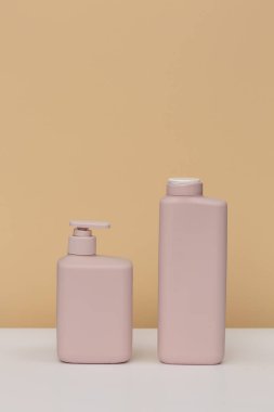 Kozmetik sabun, duş jeli, şampuan, saç kremi için bej arka planda iki soluk pembe kavanoz.