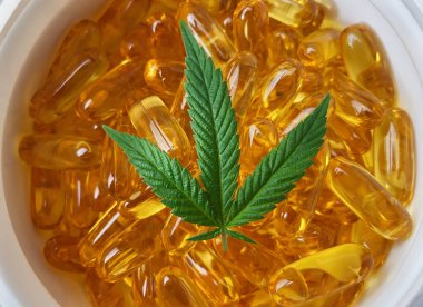 CBD yumuşak jel kapsülleri ve kenevir yaprağı ile dolu konteynırı kapat, alternatif tıp