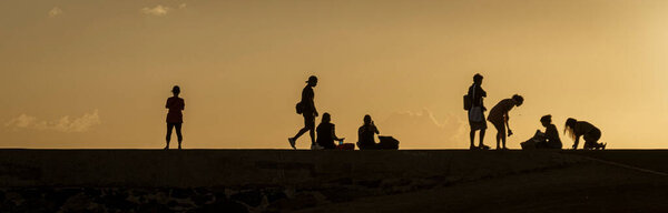 Silhouettes of people watching the sunset on Oahu, Hawaii