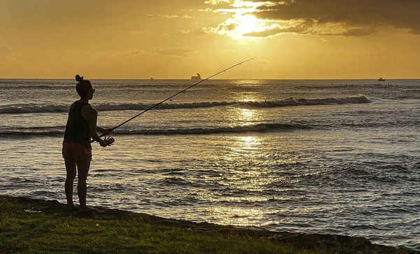 Waikiki, Honolulu, Hawaii - 31. Okt 2021-Silhouette einer Person, die bei Sonnenuntergang vom Strand aus fischt — Stockfoto