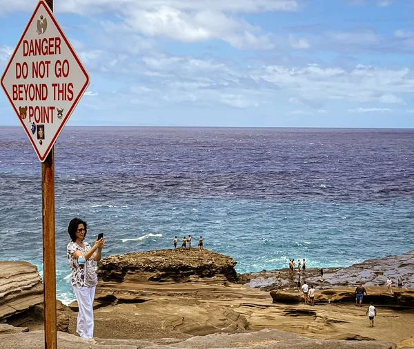 Honolulu, Hawaii - 6. Nov 2021-Menschen stehen auf Strandfelsen jenseits des Danger Do Not Go Beyond This Point-Schildes — Stockfoto