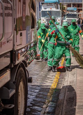Cuenca, Ecuador, Dec 24, 2021 - A team of sanitation workers cleans the streets after a parade